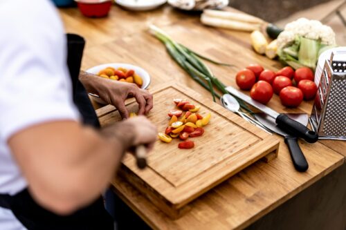 Chef in a kitchen chopping tomatoes